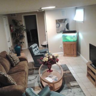 A cozy living room featuring a couch, chair, and a television, with an aquarium adding to the decor.
