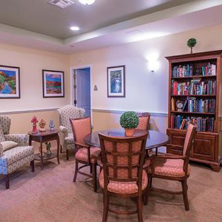 A cozy living room with a round table, chairs, and a bookshelf.