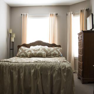 A cozy bedroom with a neatly made bed and curtains drawn.