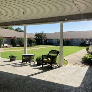 A peaceful courtyard with chairs and a lush green garden.