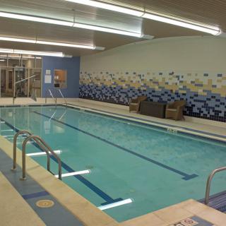 A modern indoor swimming pool with lounge chairs and a stylish tile design.