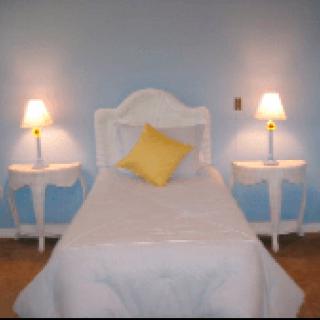 A cozy bedroom with a single bed, flanked by two nightstands and lamps.