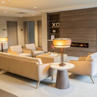 A modern, luxurious lobby seating area with beige sofas and a central table lamp.