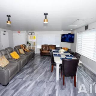 A modern living room with a sofa, dining area, and a wall-mounted television.
