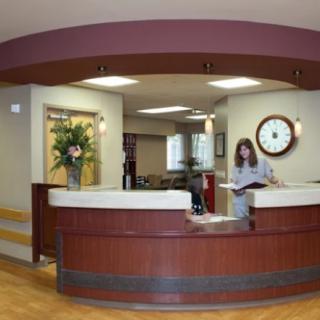 A reception area with a curved desk and a person standing behind it.