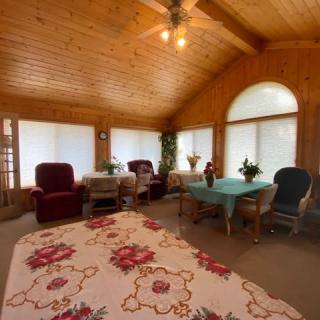 A cozy sunroom with wooden interiors, featuring comfortable seating arrangements and ample natural light.