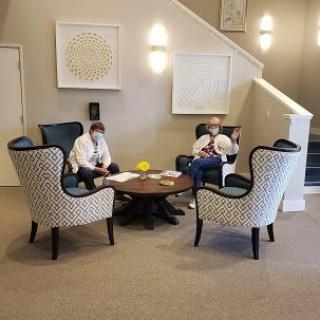 Two people sitting in a lobby lounge area with patterned armchairs and a small table.