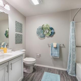 A modern bathroom featuring stylish decor, with a shower curtain, neatly arranged towels, and decorative wall art.