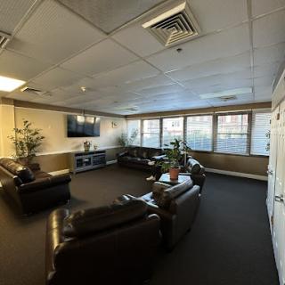 A cozy lounge area featuring comfortable sofas, indoor plants, and a TV.