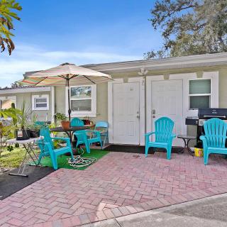 A cozy patio area with turquoise chairs, a table with an umbrella, and a grill.