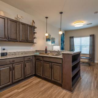 A modern kitchen with wooden cabinets and pendant lighting.