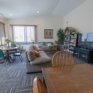 A spacious living room with a dining area, featuring a couch, television, and bookshelves.
