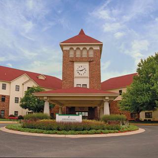 A red-roofed building with a prominent clock tower and landscaped entrance.