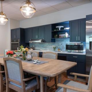 A modern kitchen and dining area featuring a wooden table with chairs, stylish pendant lighting, and sleek cabinetry.