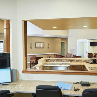 A modern office reception area with a desk, computer, and chairs.