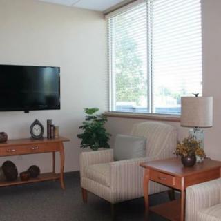 A cozy living room with a sofa, lamp, table, and television near a large window.