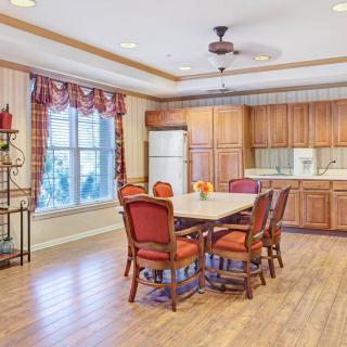 Spacious kitchen and dining area with wooden cabinets and red-cushioned chairs.