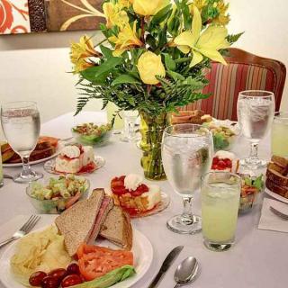 An elegantly set dining table with a variety of foods and drinks, adorned with a flower arrangement.