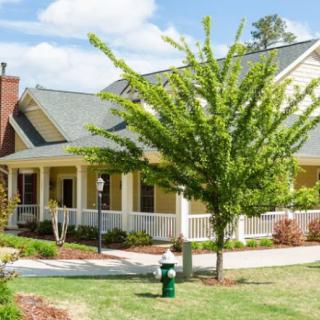 A charming suburban house with a porch and well-maintained lawn.