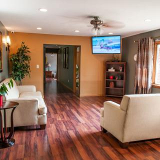 A modern living room with wooden flooring, furnished with comfortable sofas and a wall-mounted television.