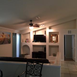 A cozy living room featuring a television, sofa, ceiling fan, and decorative elements.
