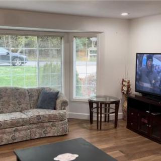 A cozy living room with a floral sofa, television, and large window.