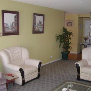 A cozy living room with two white sofas, wall art, and a potted plant.