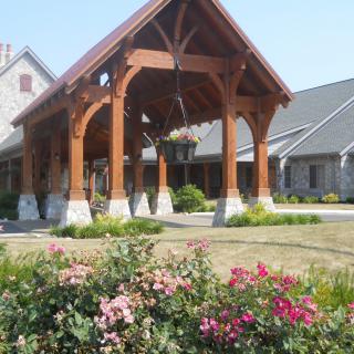 A picturesque building featuring a wooden entrance, surrounded by a well-maintained garden with colorful flowers.