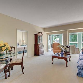 A traditional living room with a dining area, featuring elegant wooden furniture and large windows.