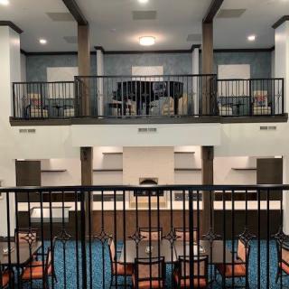 A modern hotel lobby with a seating area and upper-level balcony.