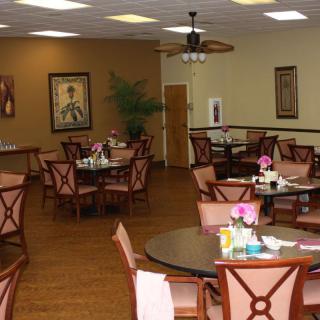A cozy dining room with neatly arranged tables and chairs, featuring elegant decor and soft lighting.