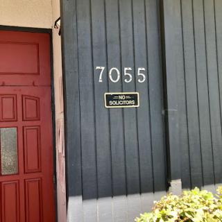 The entrance of a building featuring the address number 7055.
