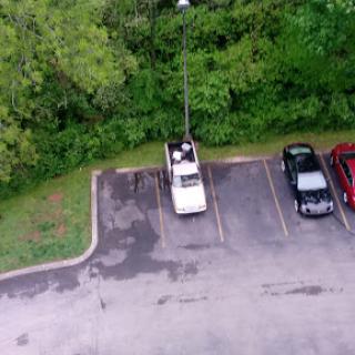 An overhead view of a parking lot featuring various vehicles and surrounding greenery.