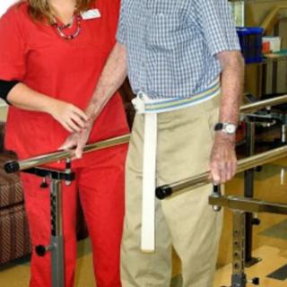 An elderly person engages in physical therapy with the assistance of a healthcare professional.