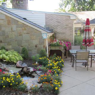 A cozy patio garden with outdoor furniture and colorful flowers.
