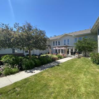 A view of a house with a well-maintained lawn and garden on a sunny day.