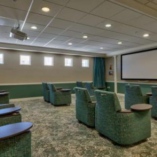 A modern home theater with plush recliner seating and a large projector screen.