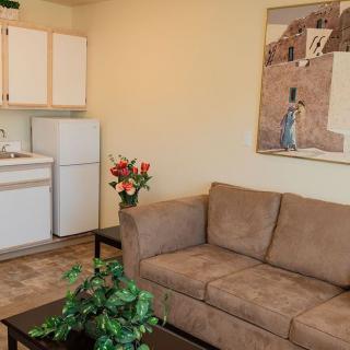A cozy living area featuring a brown sofa, kitchenette, and wall art.