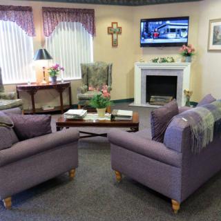 A cozy living room with purple sofas and a fireplace, featuring a television and tasteful decor.