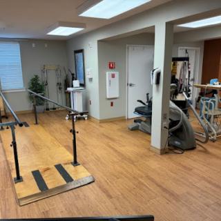 A well-equipped physical therapy room featuring exercise bars, various machines, and a spacious layout for rehabilitation activities.