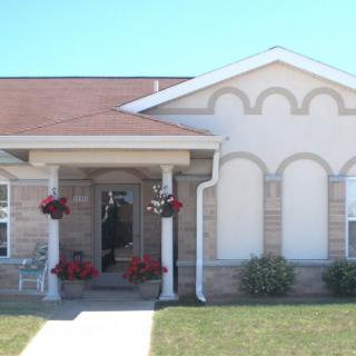 A single-story house with a front porch and manicured lawn under a clear blue sky.