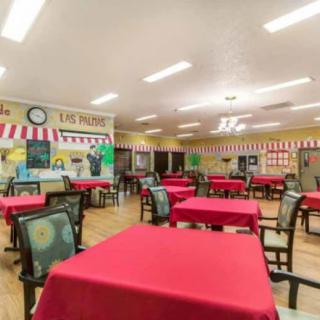 An empty dining area with red tablecloths and decorated walls.