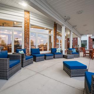 A spacious covered patio with comfortable wicker furniture and blue cushions, set against a brick building.