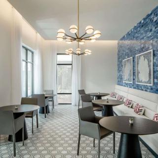 A modern dining area featuring stylish furniture, a unique chandelier, and a vibrant blue accent wall.