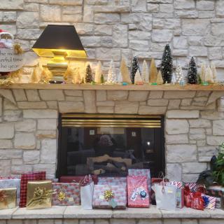 A cozy stone fireplace adorned with Christmas decorations and gifts on the mantel, capturing the holiday spirit.