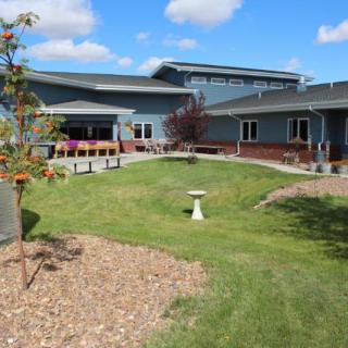 A modern building surrounded by a landscaped garden under a partly cloudy sky.