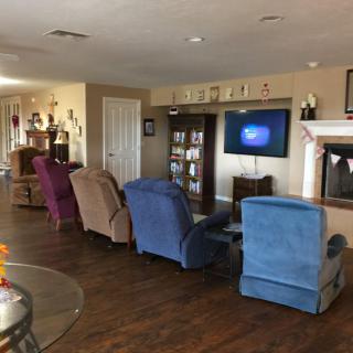 A cozy living room with multiple recliners facing a television and a fireplace.