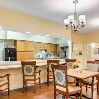 A cozy dining area with wooden chairs and tables adjacent to a kitchen.