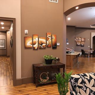 A cozy living room with modern decor, featuring artwork on the wall and wooden flooring.