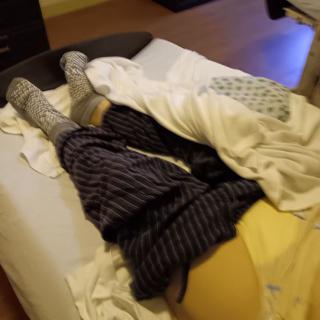 A person comfortably sleeping in bed, wrapped in blankets and wearing cozy socks.